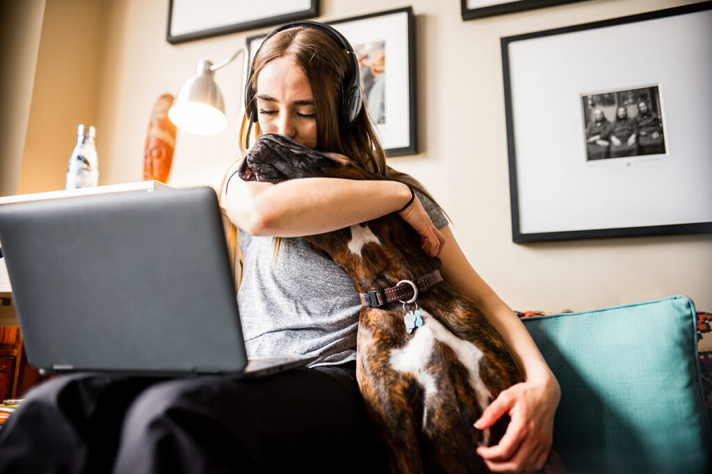 Young woman working from home kissing her dog